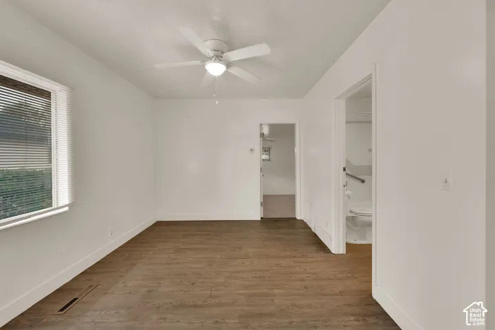 Room featuring wood-finish flooring, white walls, and a ceiling-mounted light fixture with integrated fan