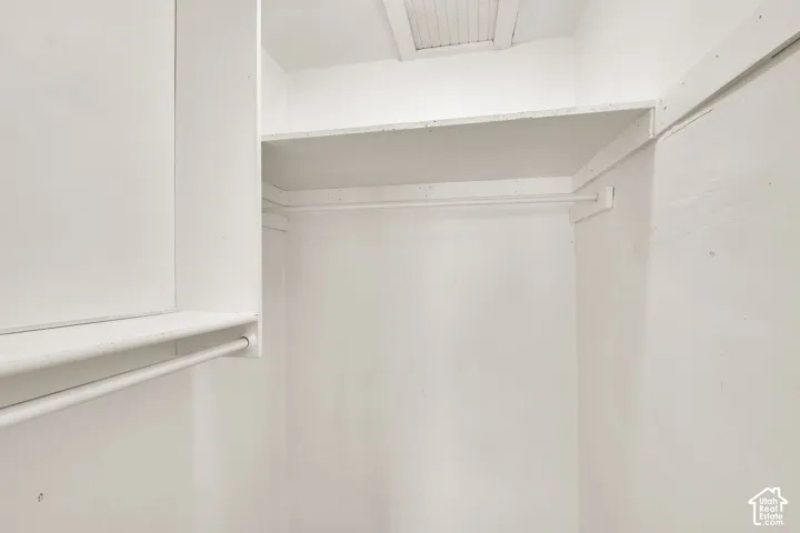 Storage area featuring dual-level shelving and integrated hanging rods