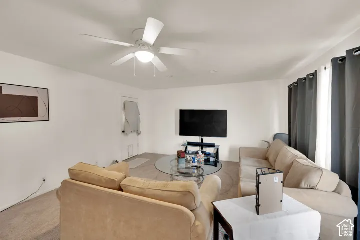UNIT ON ADAMS Neutral-toned carpeted flooring, white wall finish, and a ceiling-mounted fan with integrated lighting, used as a living room now.