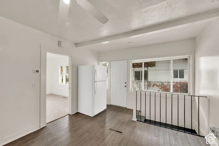 Wood-finish flooring, large picture window, metal stair railing, and ceiling-mounted fan