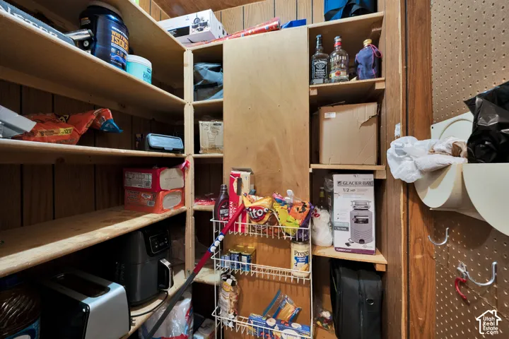 Storage space featuring tiered wooden shelving and perforated wall-mounted storage panels