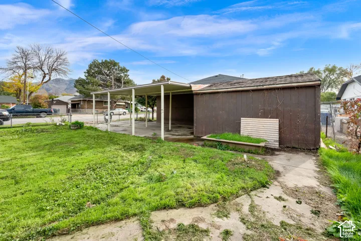 Detached structure featuring a covered carport, vertical siding, and an attached concrete walkway