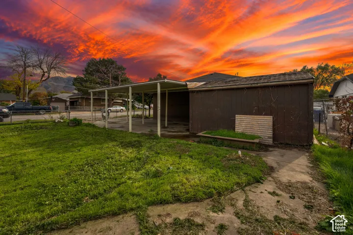 Exterior features including a covered carport, wood-panel siding, concrete surfacing, and a fenced yard