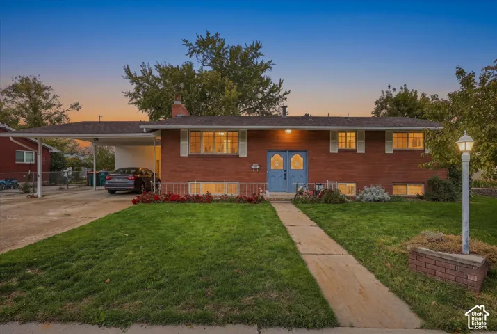 Single-story brick exterior featuring a covered carport, double-entry front doors, a concrete walkway, and a landscaped front lawn