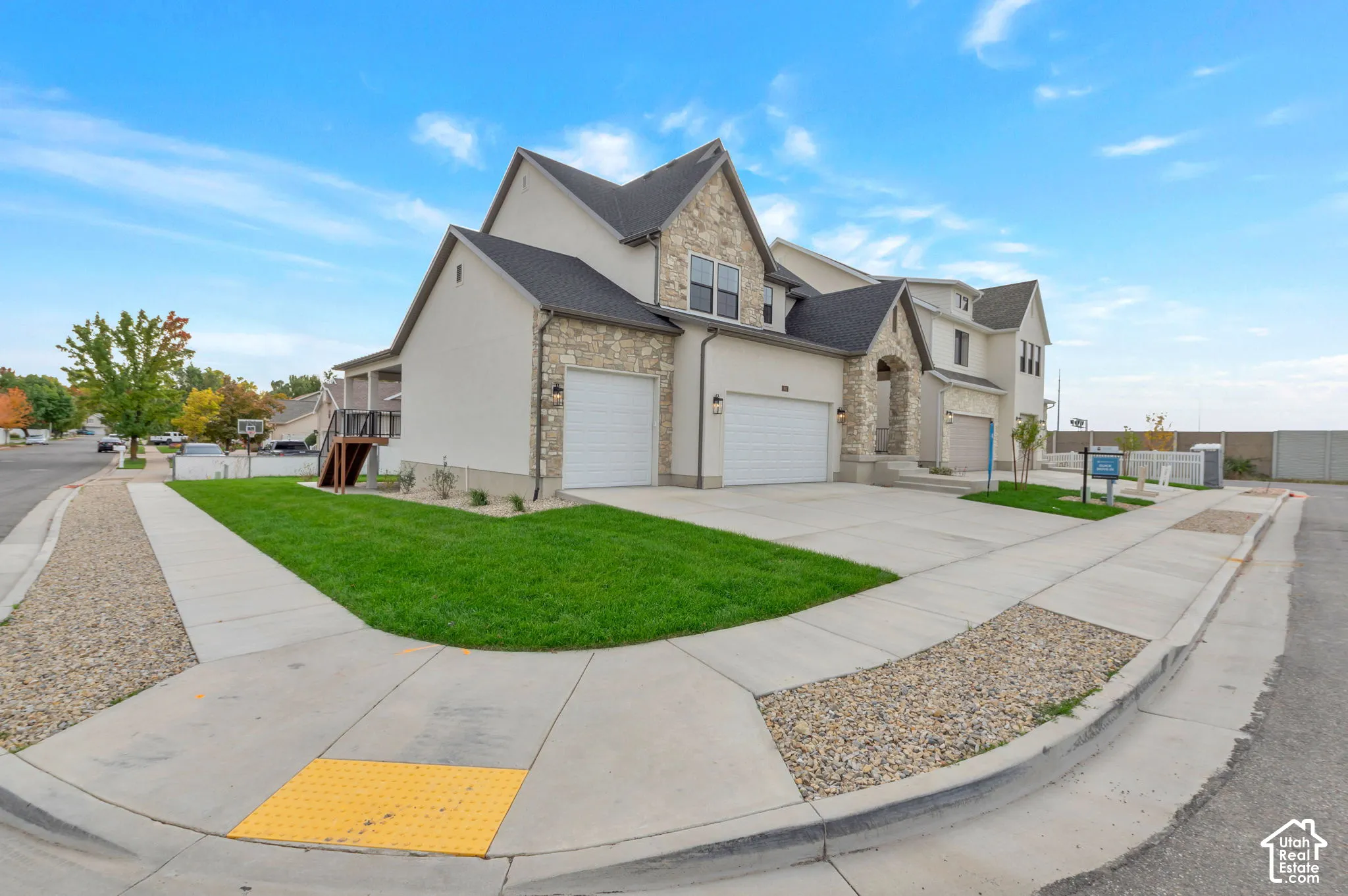 Multi-level exterior featuring stone veneer accents, stucco siding, a multi-gabled roofline, and a three-car garage