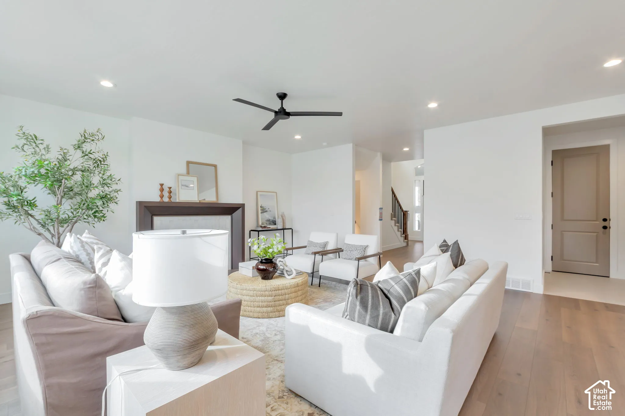 Living area featuring wood-finish flooring, recessed lighting, a modern ceiling fan, and a fireplace with a minimalist surround