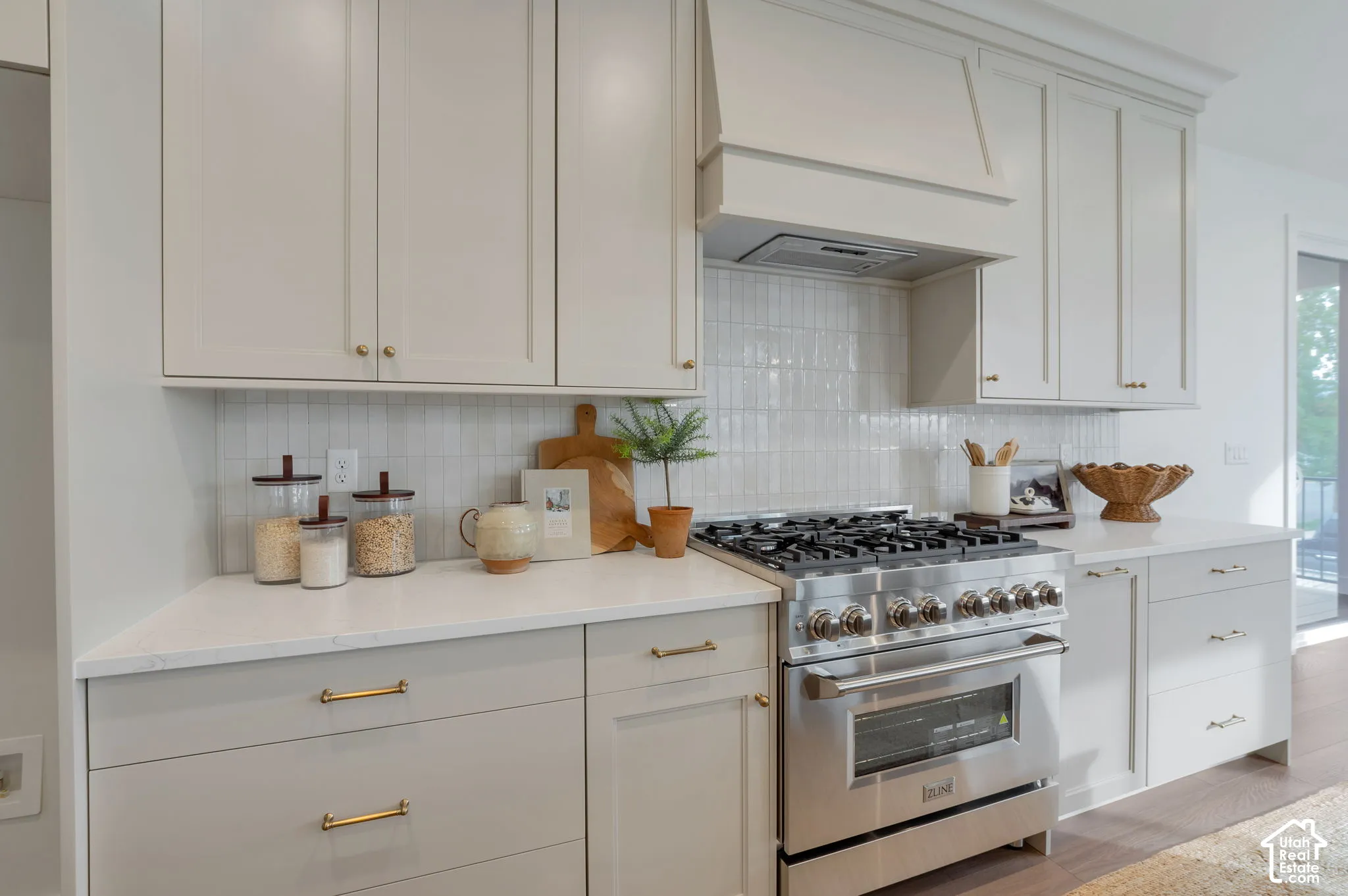Kitchen featuring shaker-style cabinetry, quartz countertops, vertical tile backsplash, stainless steel gas range, and a custom range hood