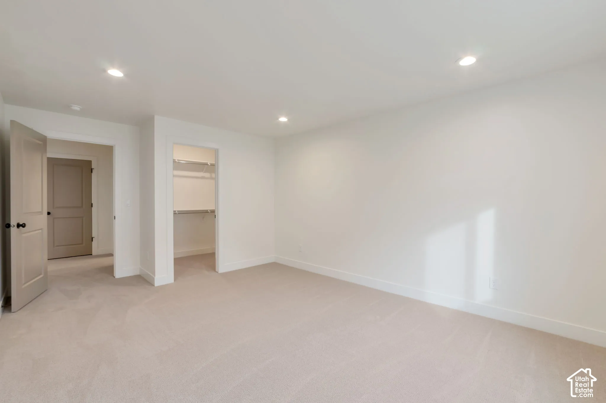 Interior space featuring neutral-toned carpeting, recessed lighting, white walls, paneled interior doors, and a reach-in closet with built-in shelving