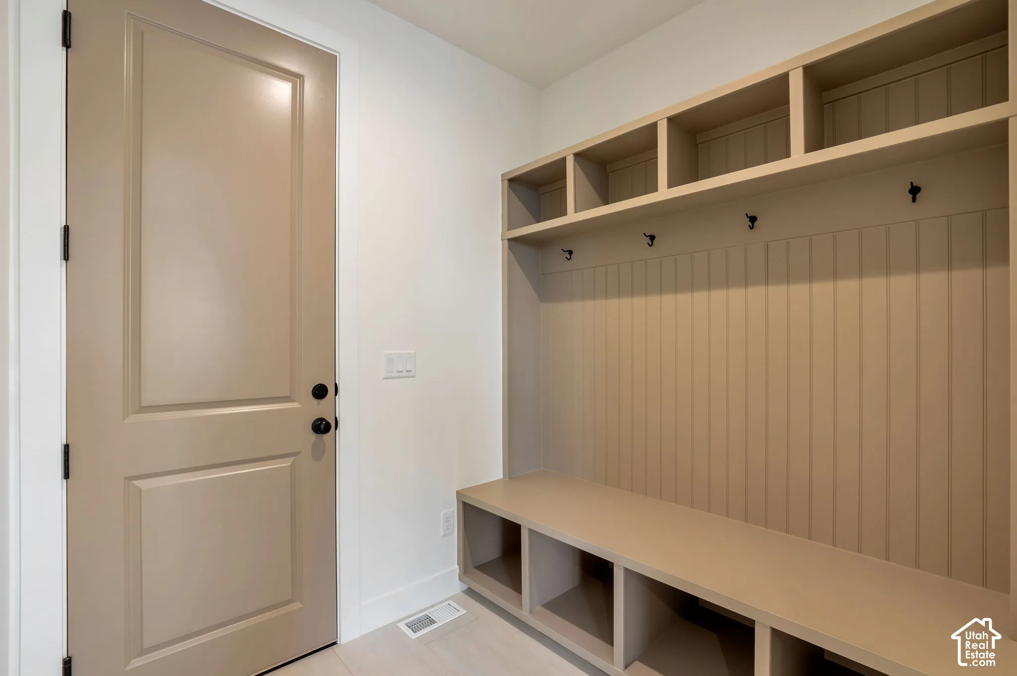 Built-in custom cabinetry featuring open shelving, beadboard detailing, integrated bench seating, and matte black hardware hooks