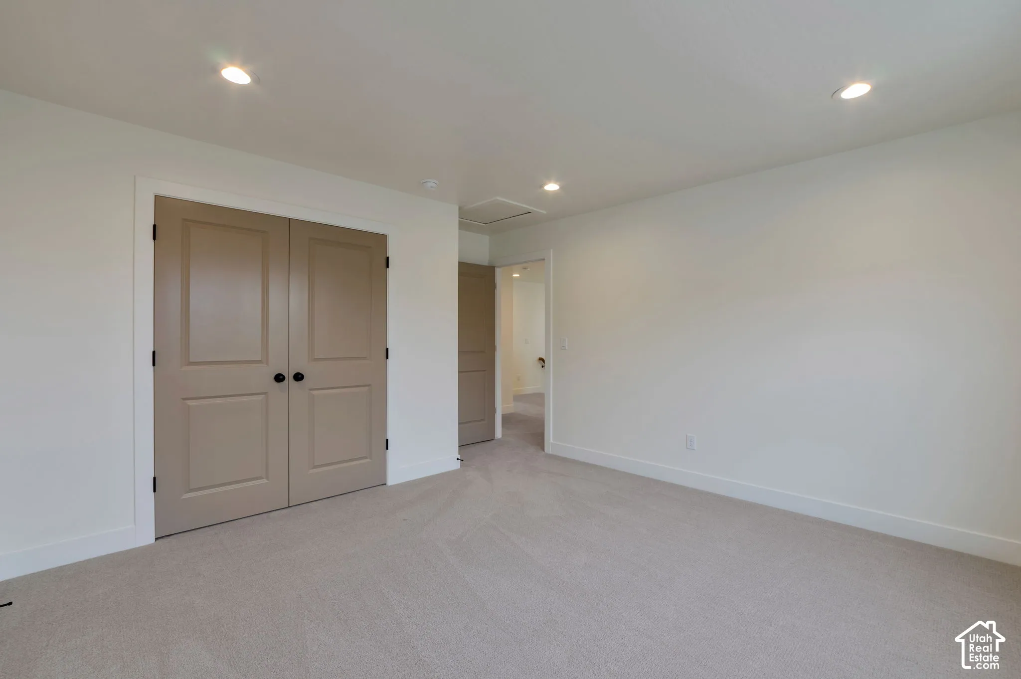 Neutral interior space featuring recessed ceiling lighting, wall-to-wall carpeting, and double-panel doors with matte black hardware