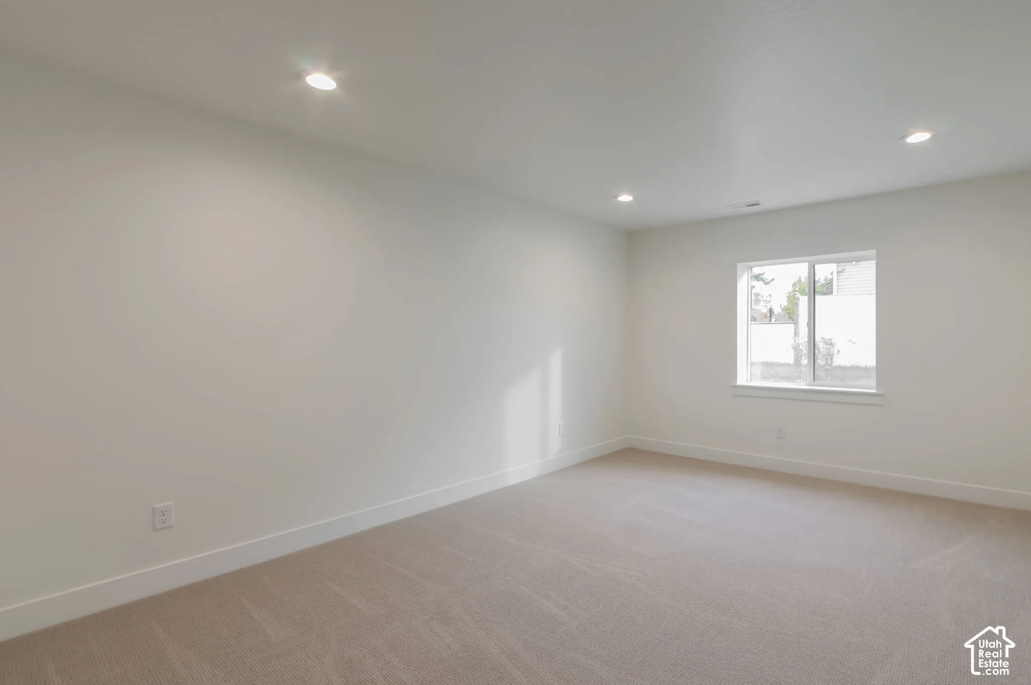 Neutral-toned wall-to-wall carpeting, recessed ceiling lighting, and a window with a white frame