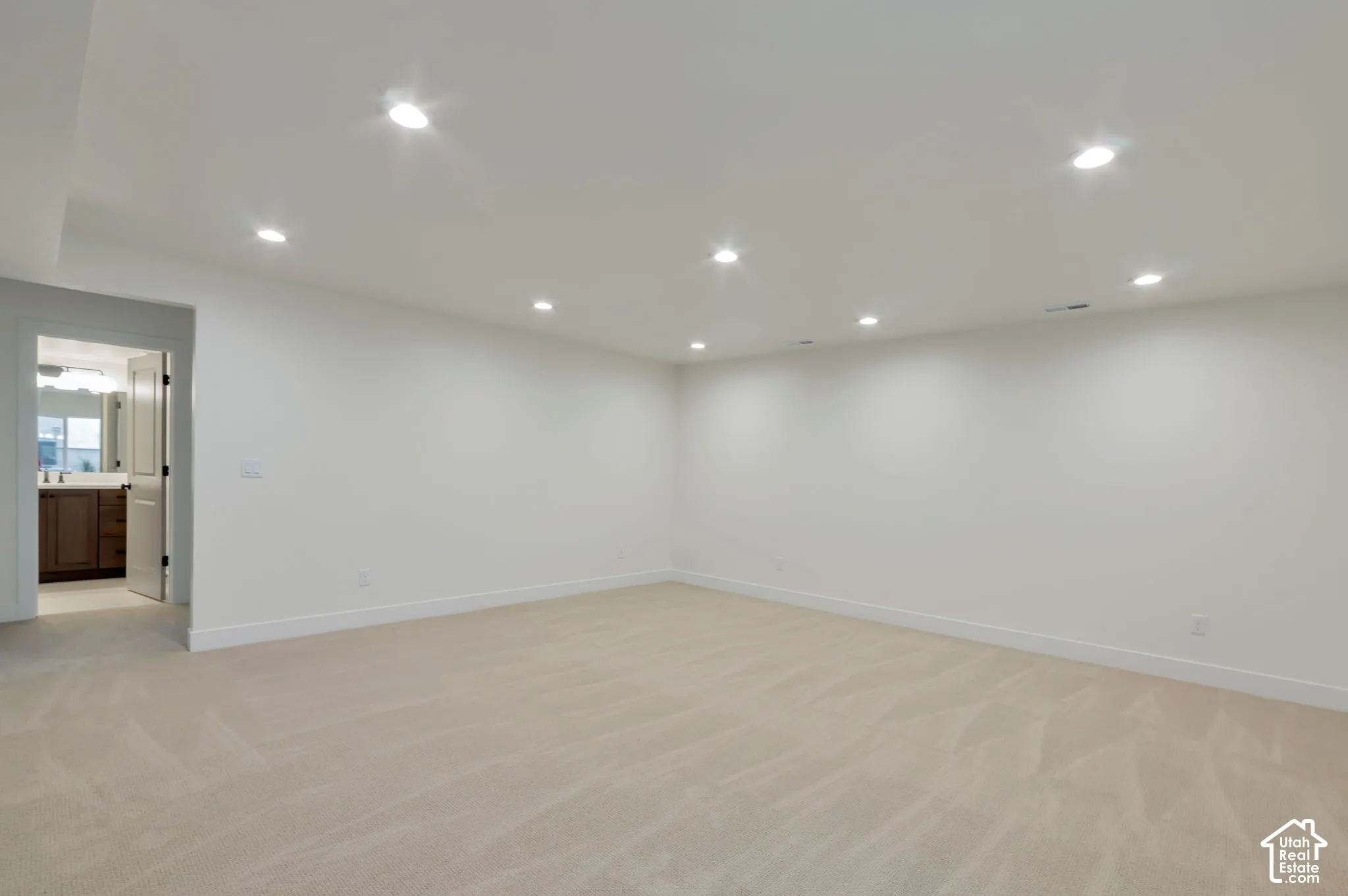 Neutral-toned wall-to-wall carpeting, recessed ceiling lighting, and smooth-finish walls