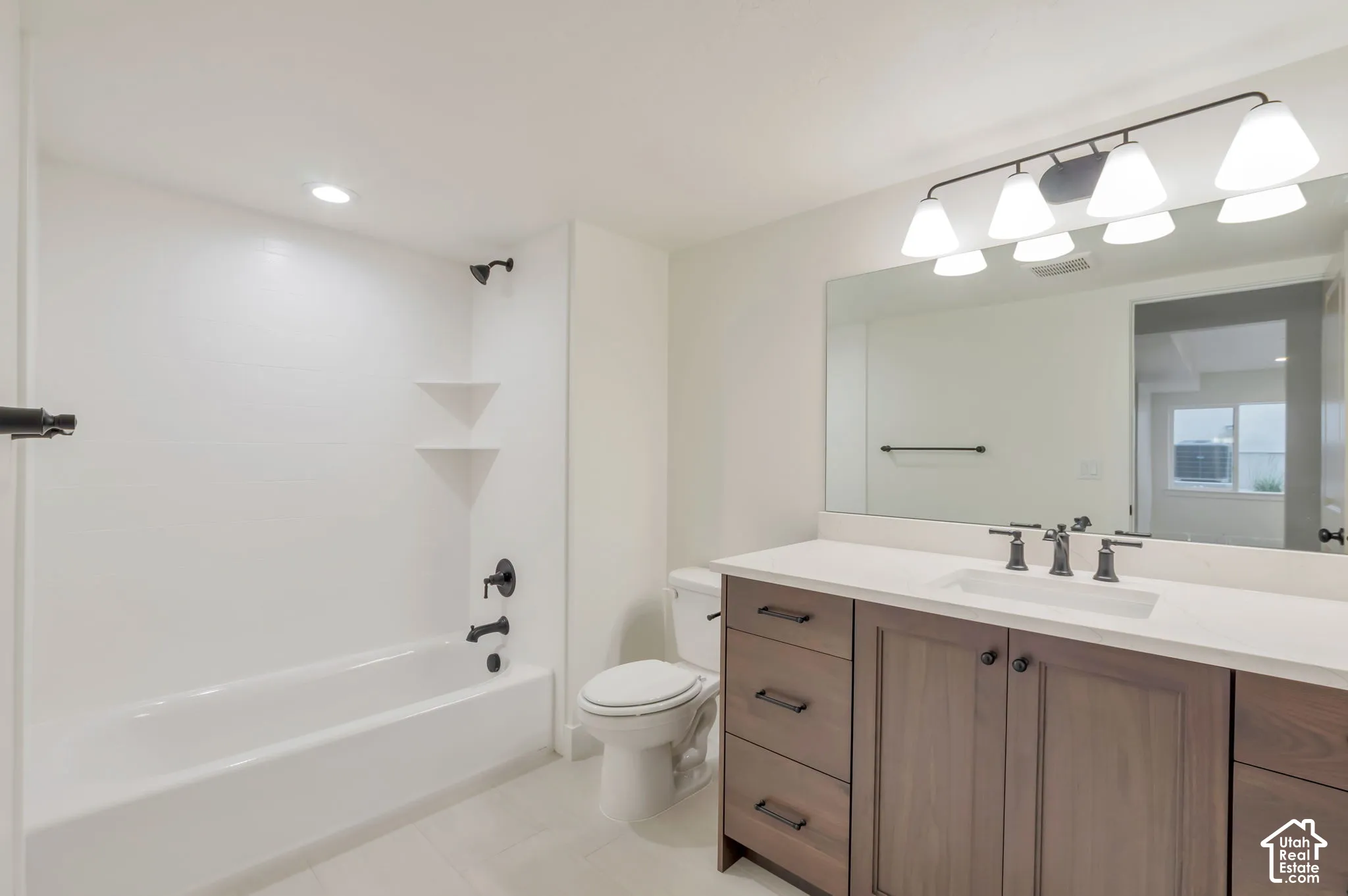 Bathroom featuring a vanity with dark wood-finish cabinetry, a stone-composite countertop, matte black hardware, a full-width mirror, and a tub-shower combination with tile surround