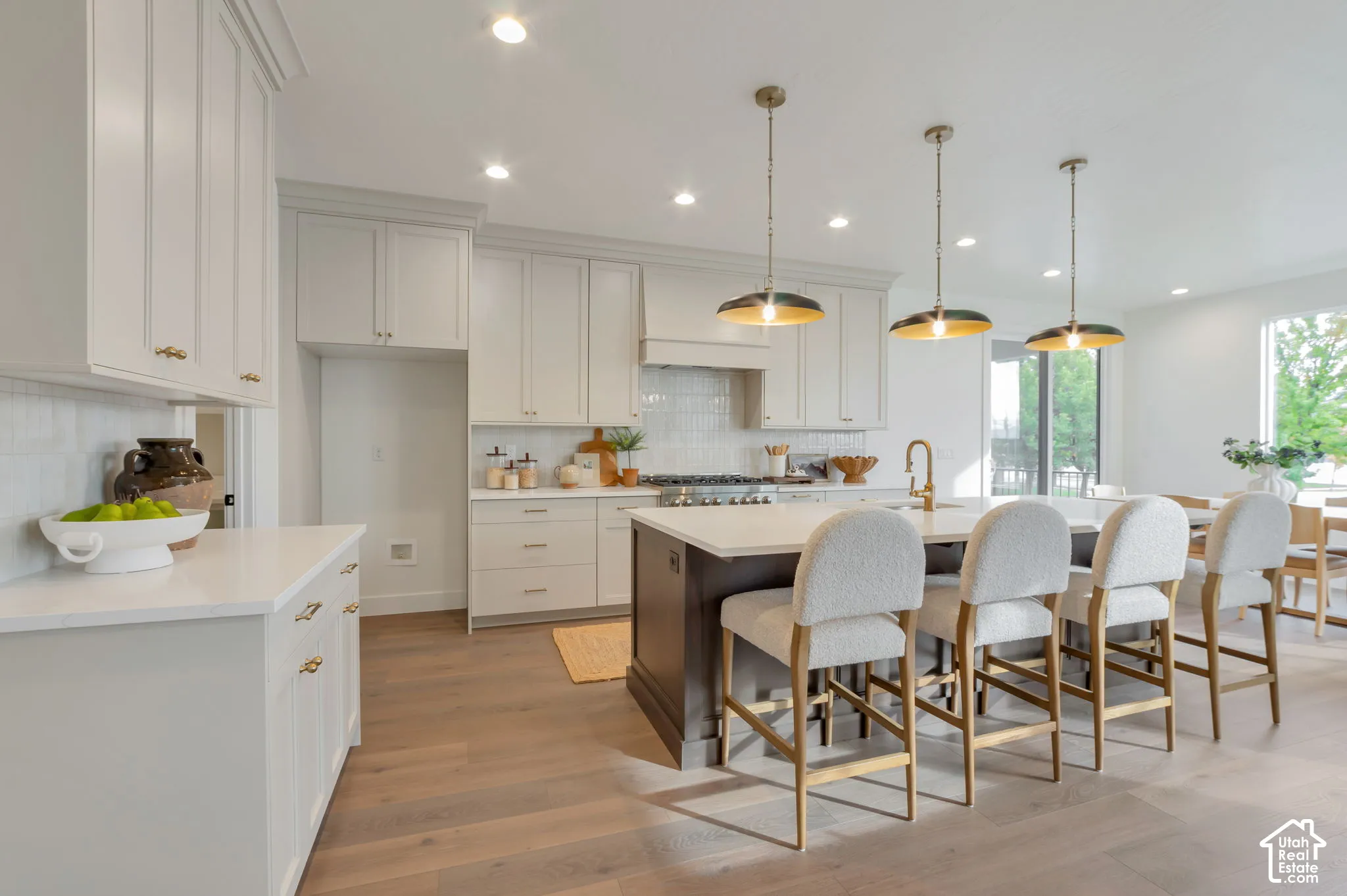 Kitchen featuring light-colored cabinetry, a contrasting central island, stone-finish countertops, tile backsplash, and wood-finish flooring