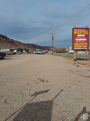 Expansive gravel lot featuring prominent roadside signage and prominent mesa rock formations