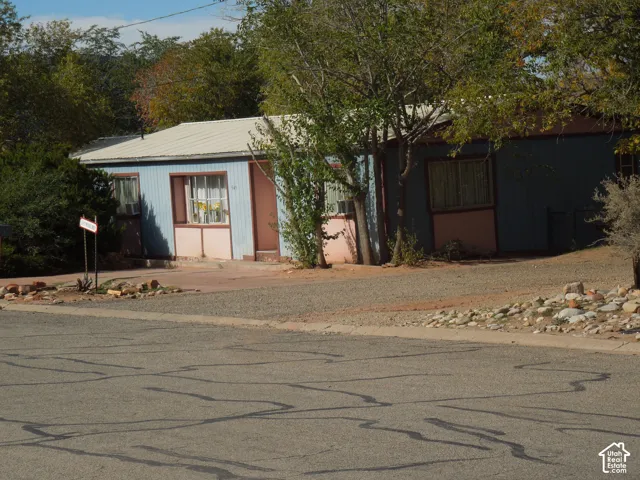 Single-story exterior featuring light blue vertical siding, metal roofing, and natural rock landscaping