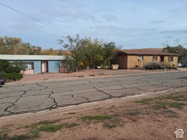 Single-story residences featuring shingle siding, metal roofing, and mature trees on a level lot with desert landscape