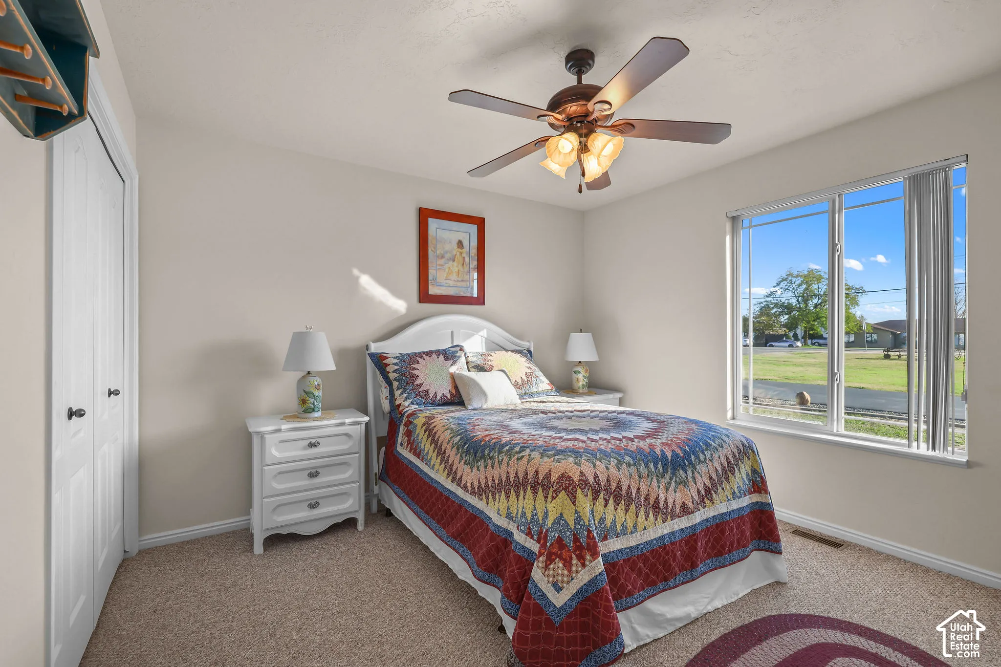 Neutral-toned interior featuring carpeted flooring, a ceiling fan with integrated lighting, and a window with blinds