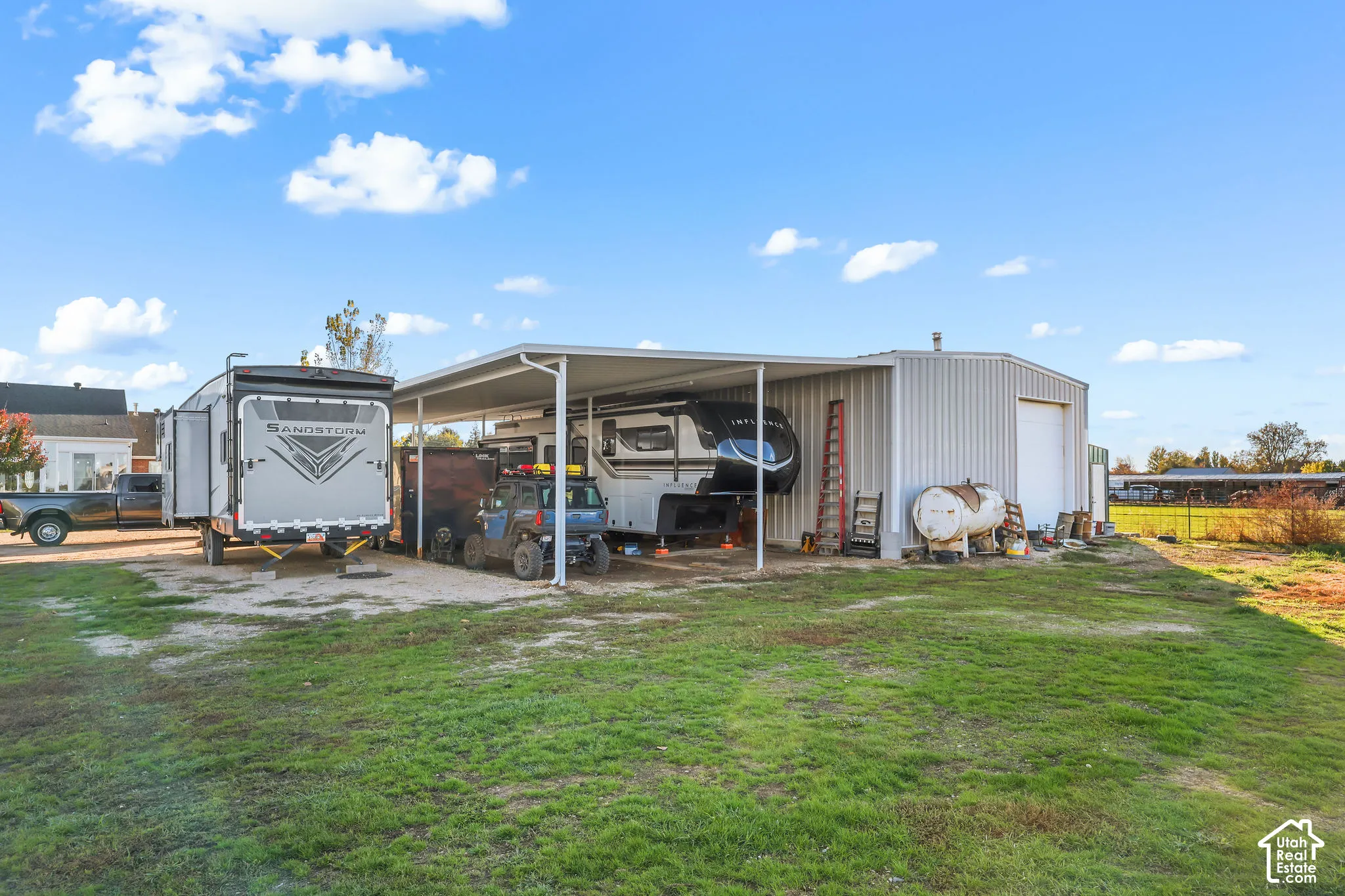 Metal-sided detached workshop featuring a covered carport, roll-up garage door, and open-air storage area