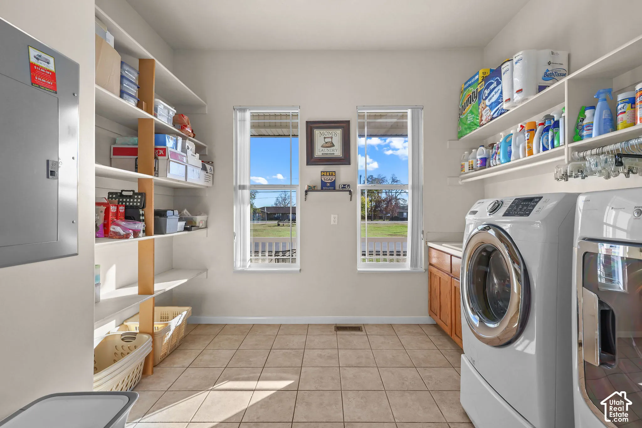 Laundry room featuring tile flooring, built-in shelving, wooden cabinetry, and dual windows