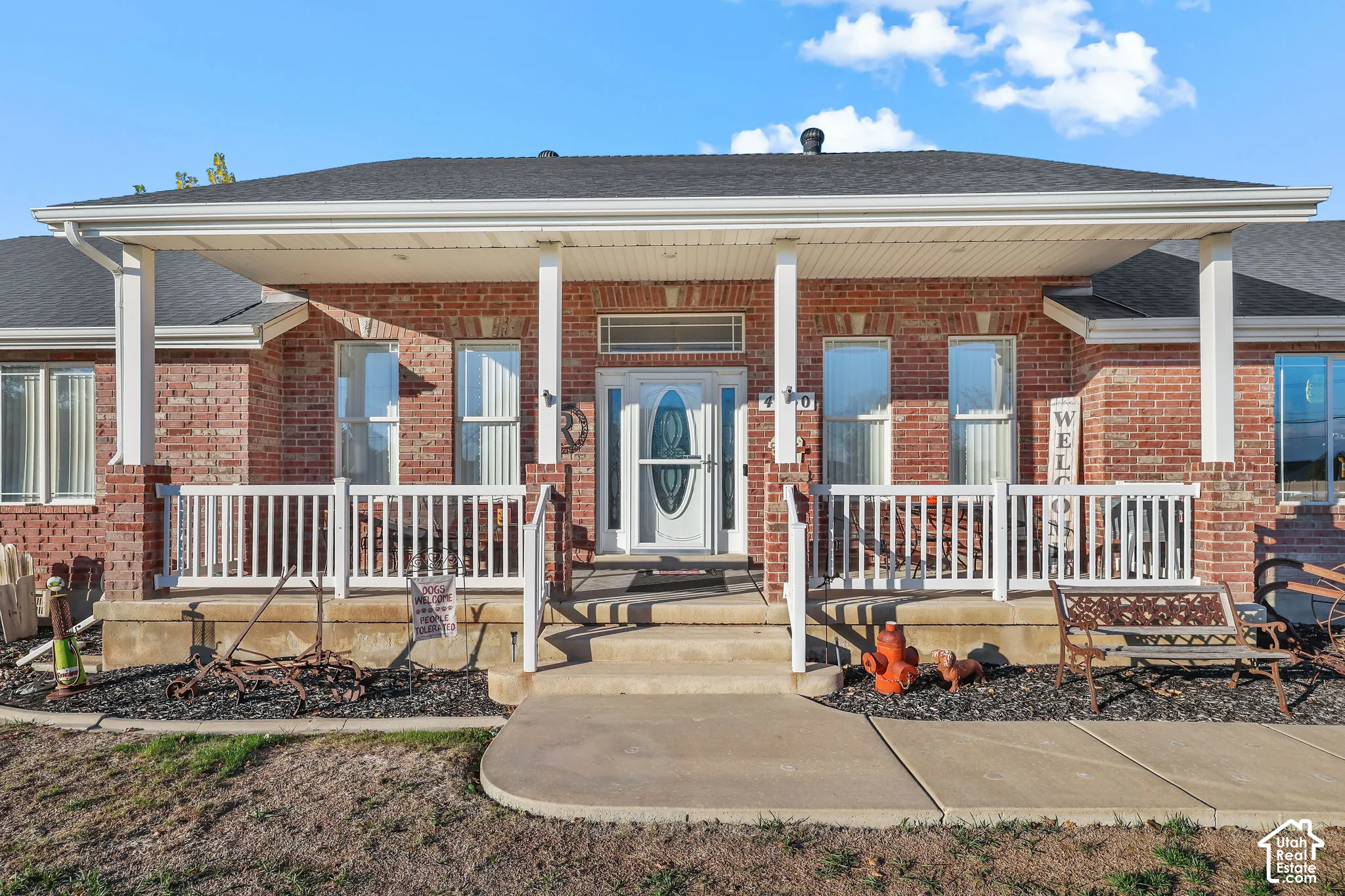 Brick exterior residence featuring a covered front porch, white railing, multi-pane windows, and a central entry door with a glass transom