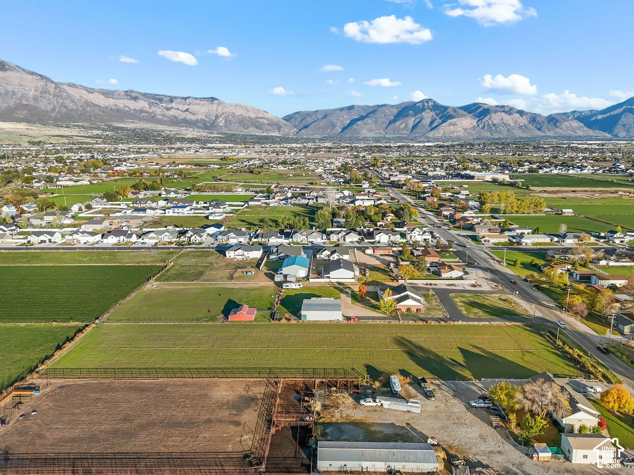 Aerial perspective featuring expansive acreage, dedicated agricultural zoning, home with multi-purpose outbuildings, and a prominent mountain range backdrop