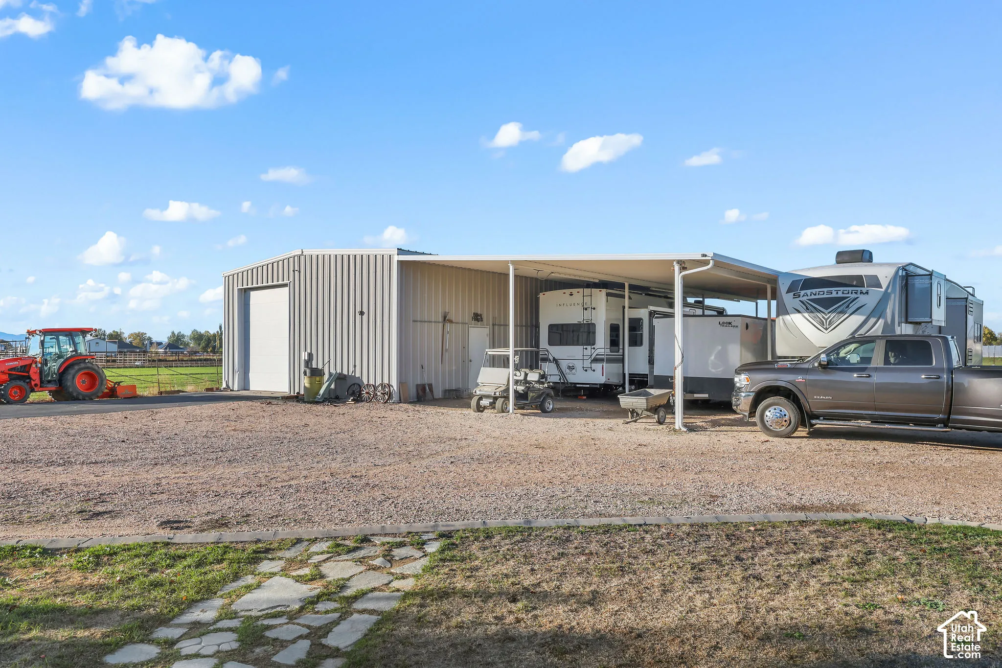Metal outbuilding featuring a large roll-up door and a permanent attached covered storage canopy