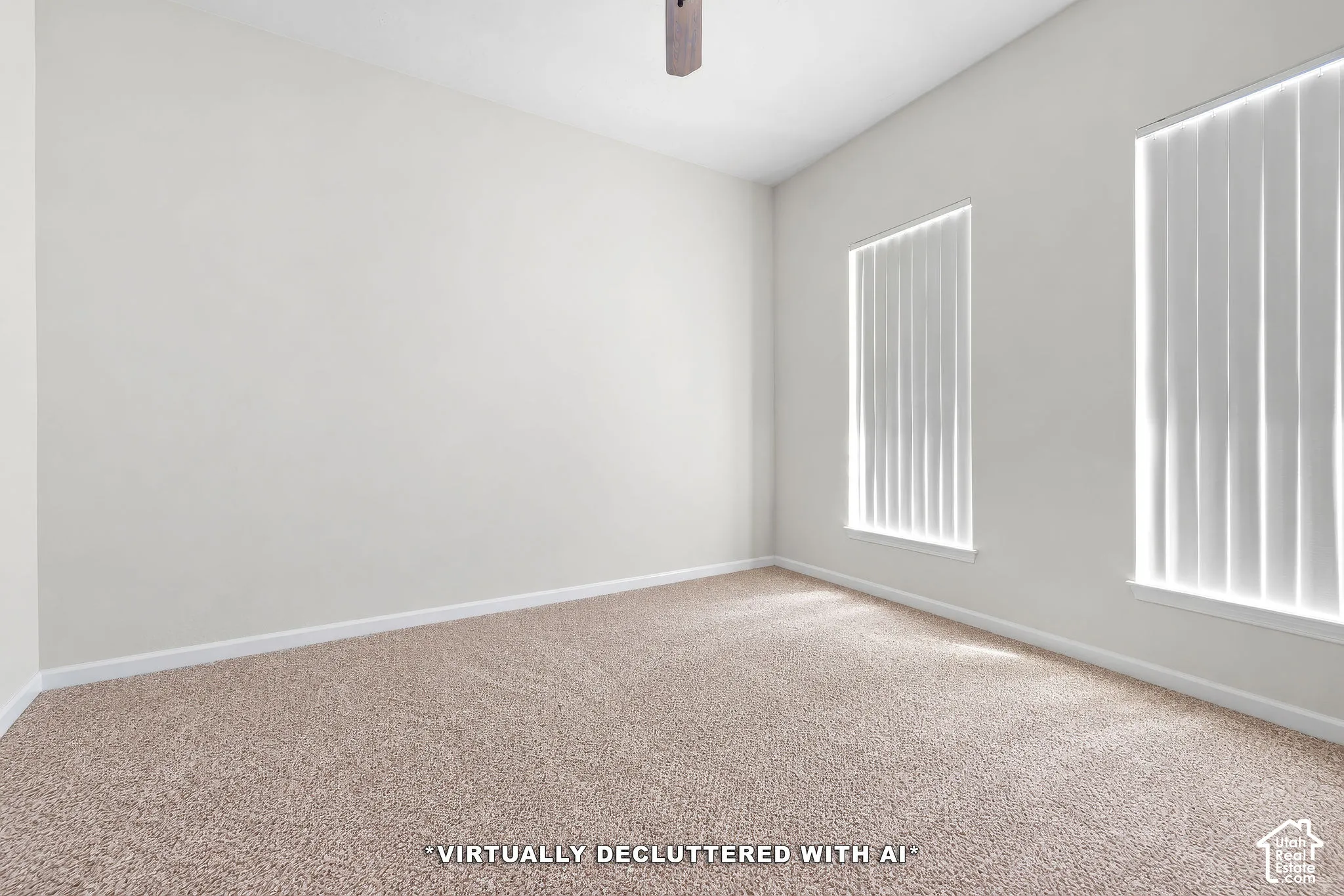 Neutral-toned interior featuring wall-to-wall carpeting, dual windows with vertical blinds, and a ceiling fan. Currently used as storage to prepare for moving.