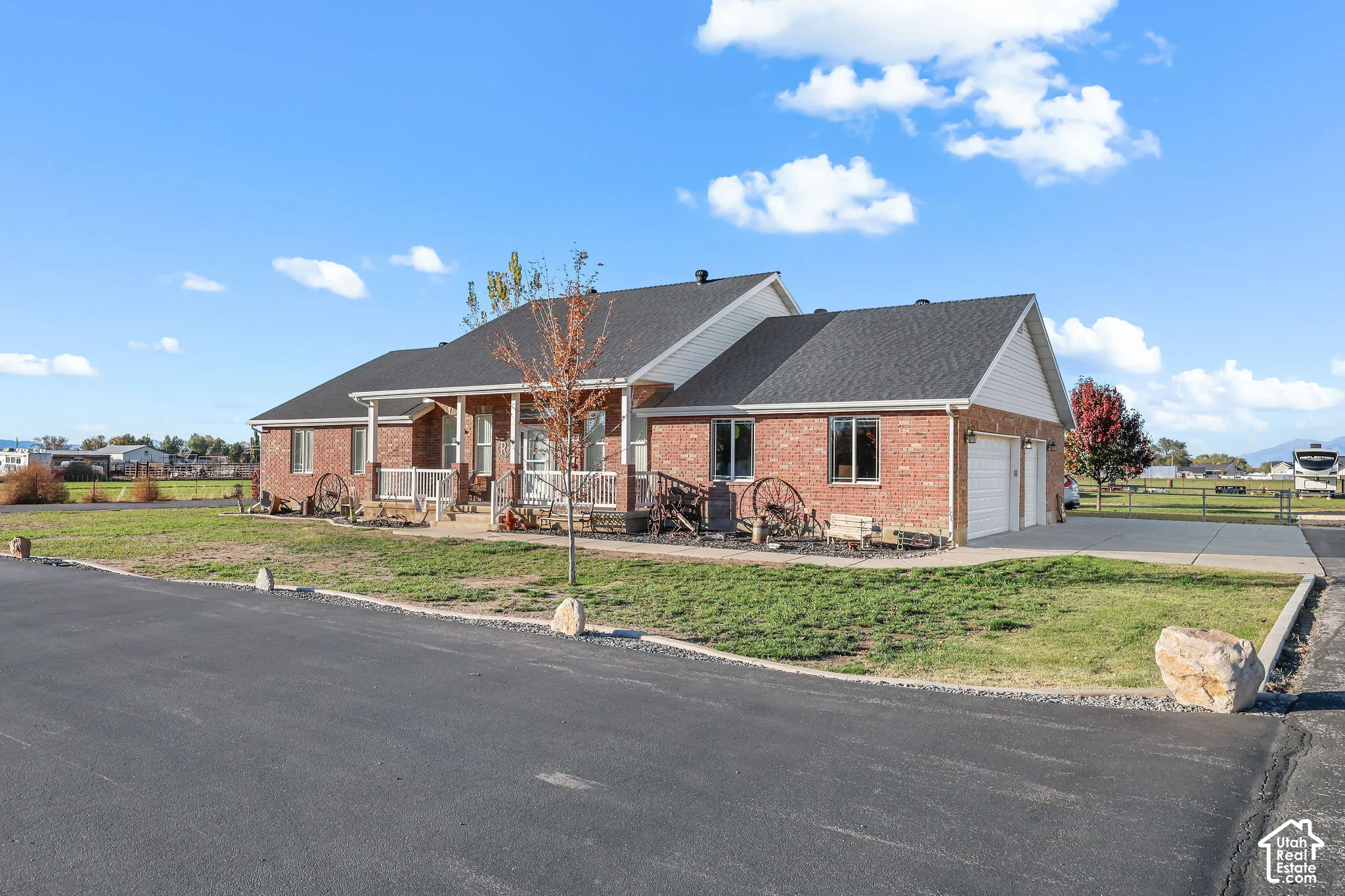 Single-story brick exterior featuring a covered front porch, asphalt-shingled roof, attached multi-car garage, and concrete driveway