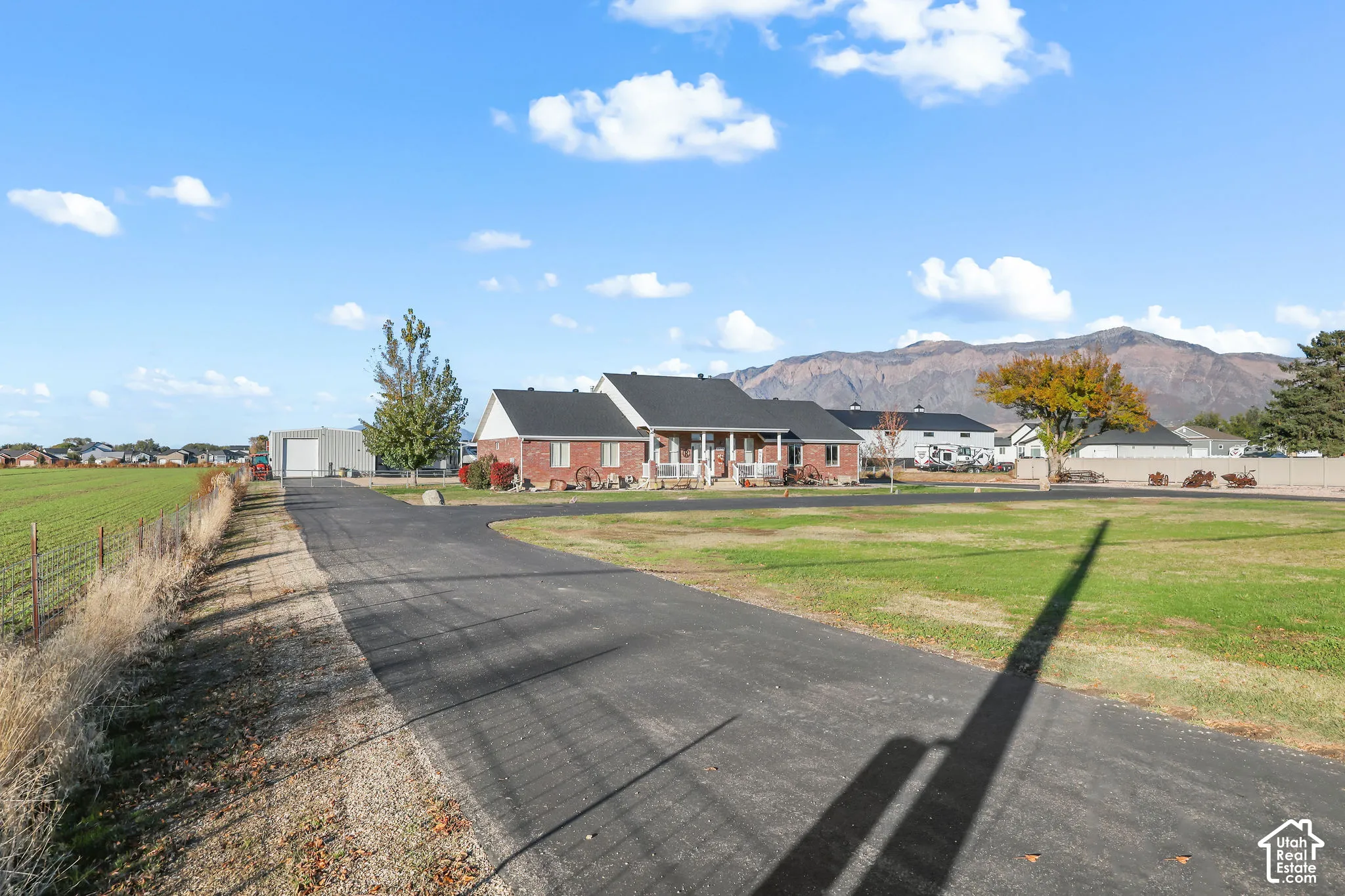 Single-level brick exterior residence featuring a covered front porch, asphalt driveway, detached metal garage, and mountain backdrop