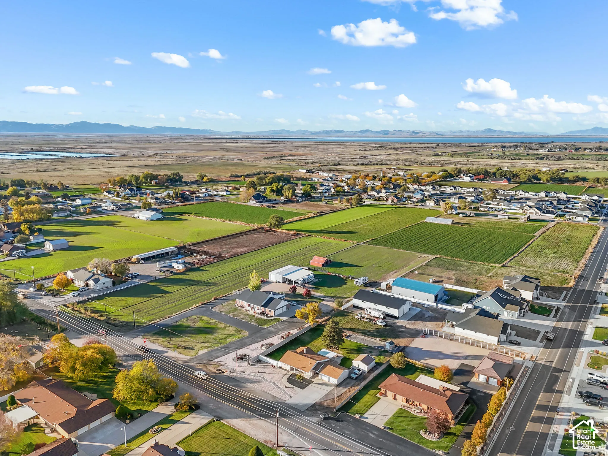 Aerial perspective featuring expansive acreage, paved street access, and mountain range backdrop