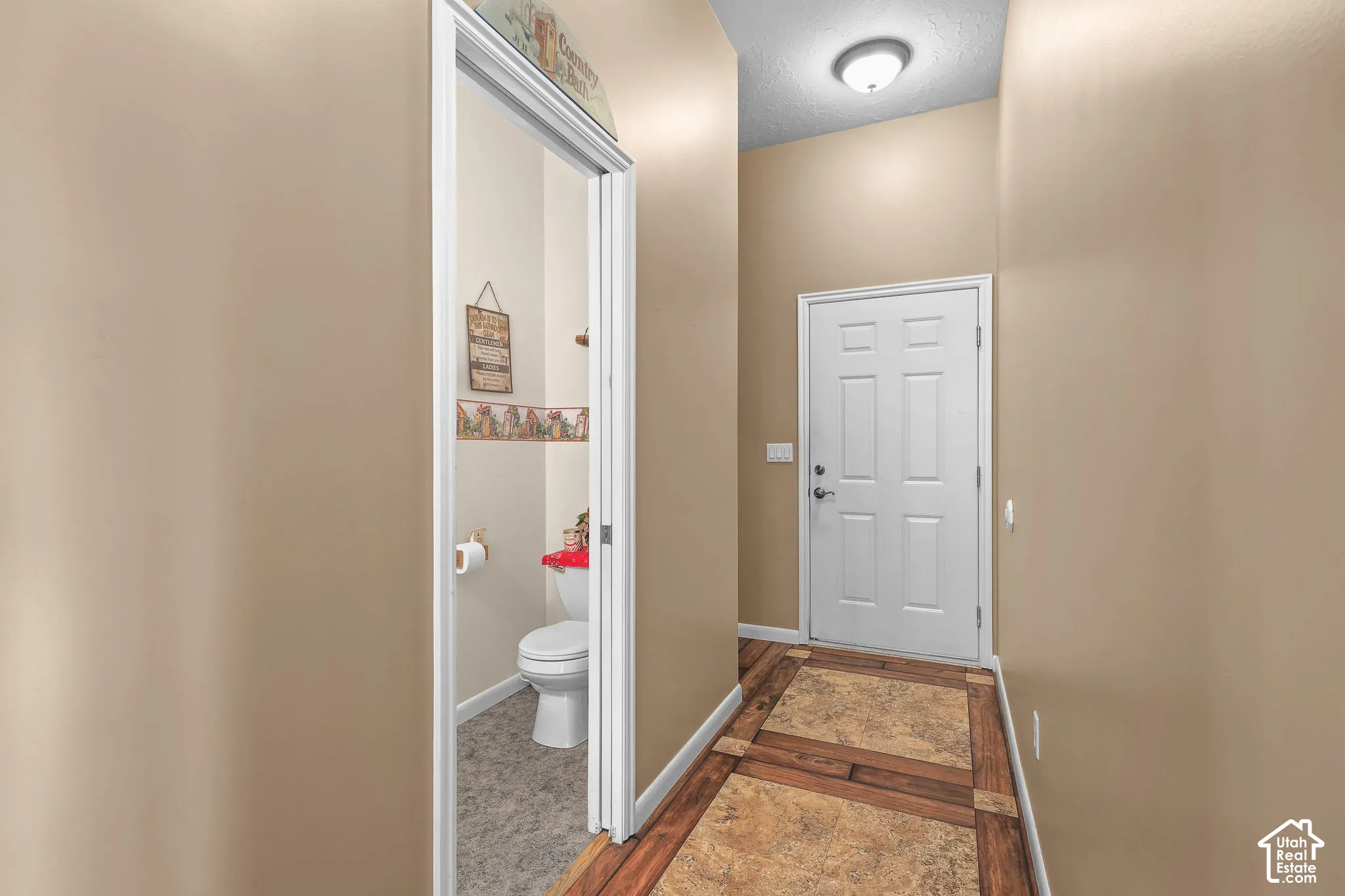 Entry area featuring high ceilings, a white six-panel door, and custom tile flooring with decorative wood-look borders