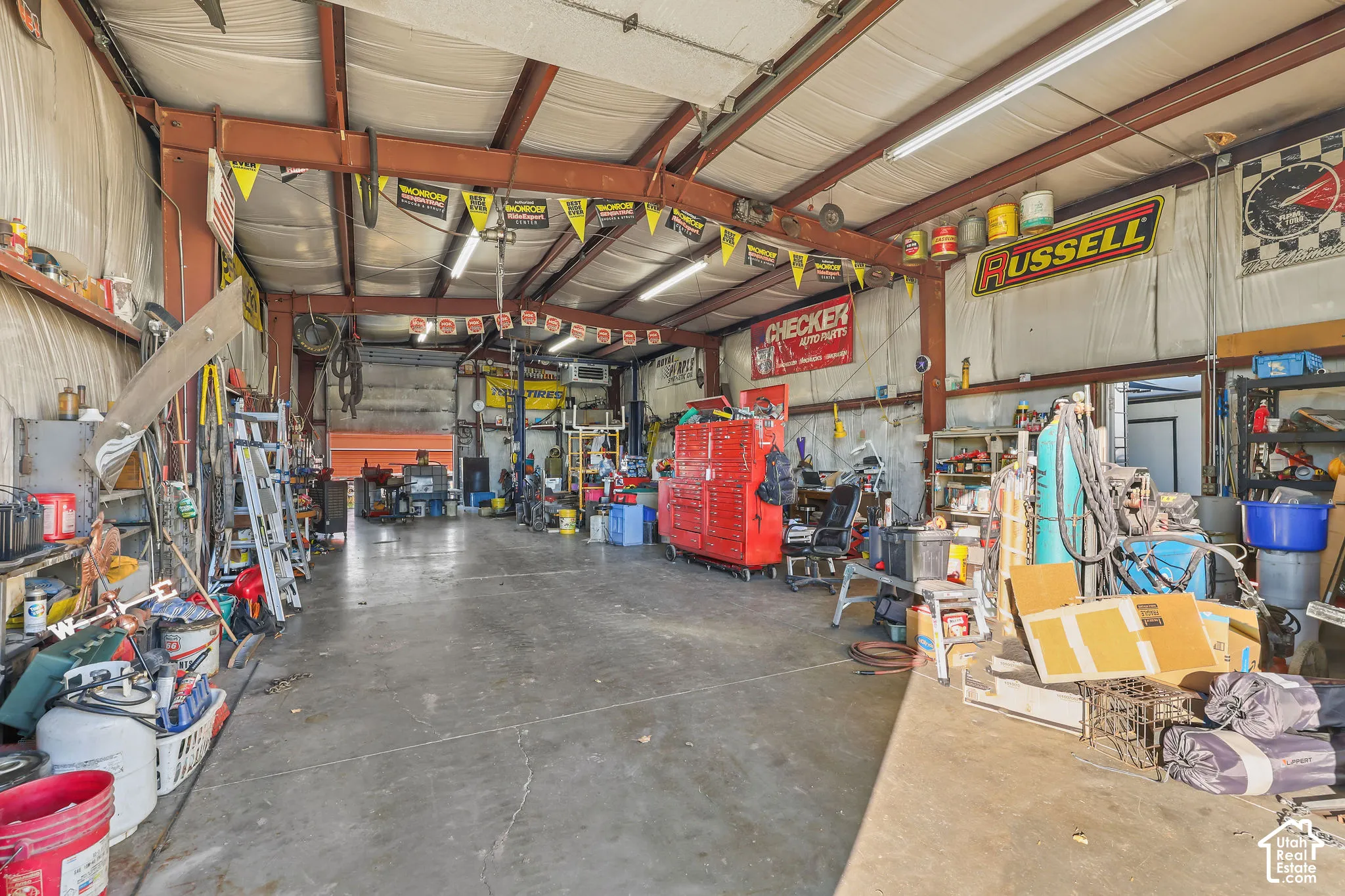 Expansive metal-framed workshop featuring concrete flooring, exposed steel beams, high-clearance ceiling, and integrated fluorescent lighting