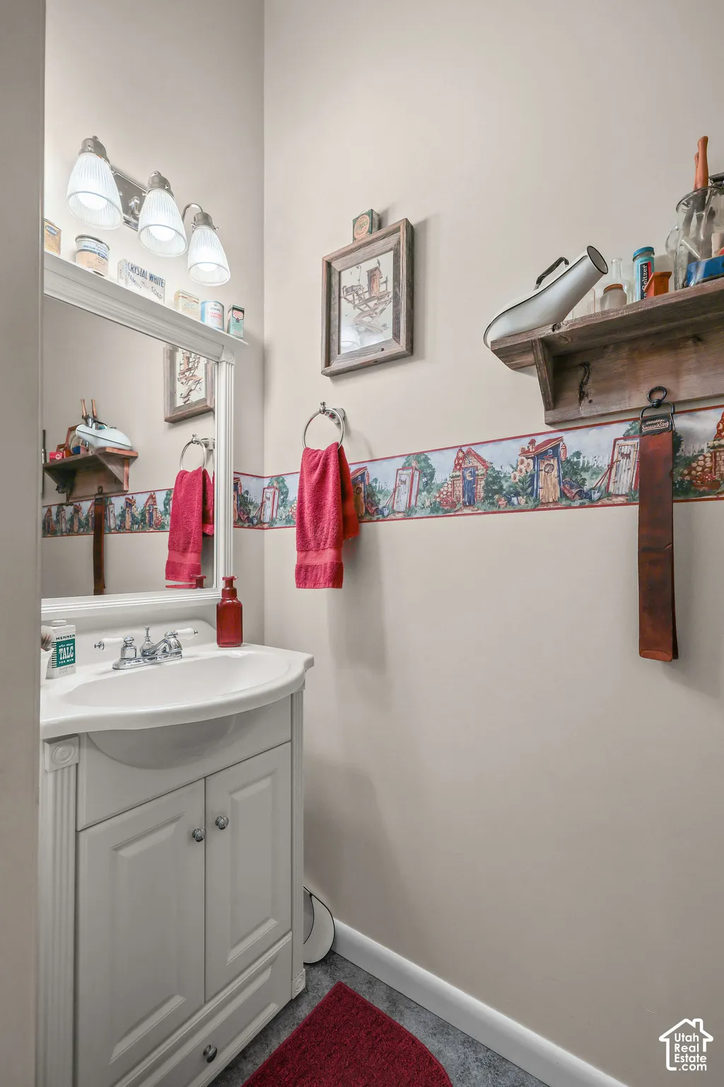 White vanity featuring a molded sink basin, polished metal faucet, integrated cabinetry, and an attached framed mirror with a tri-light fixture