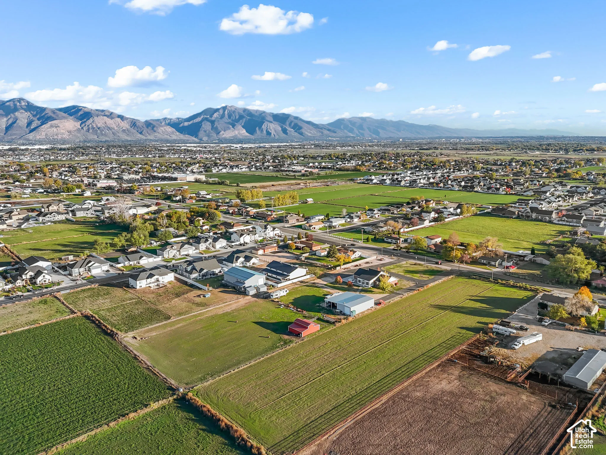 Aerial perspective featuring expansive acreage, fenced perimeter boundaries, and mountain range backdrop