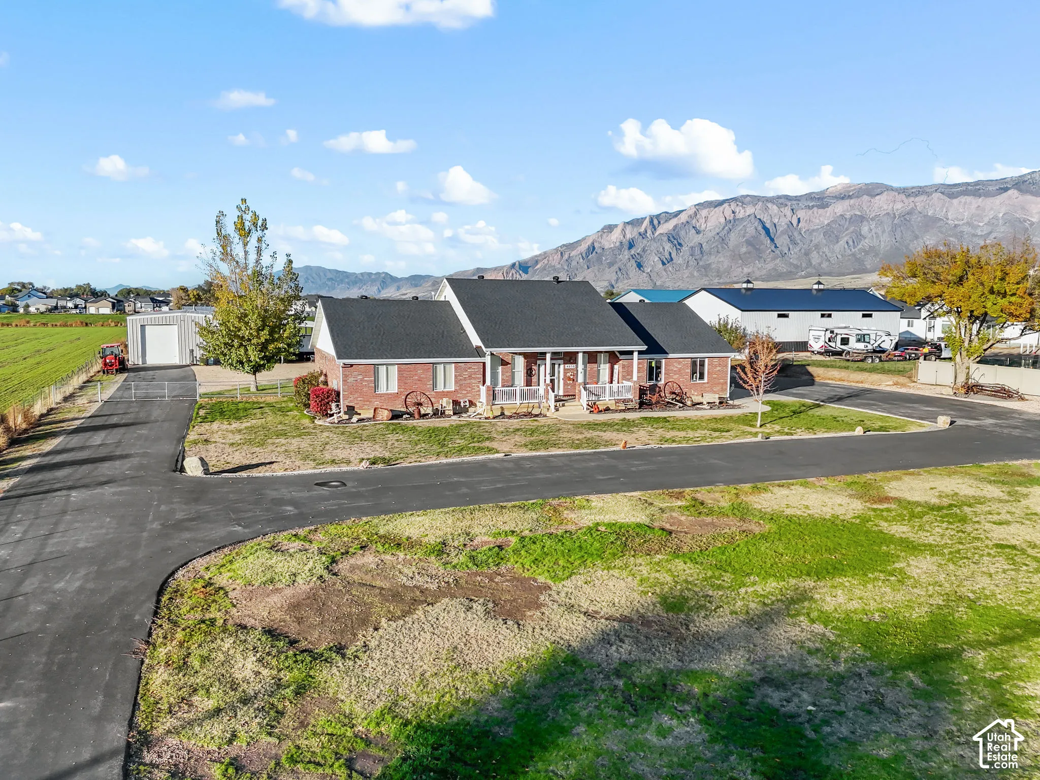 Brick exterior residence featuring a covered front porch, asphalt-paved driveway, detached workshop, and mountain backdrop