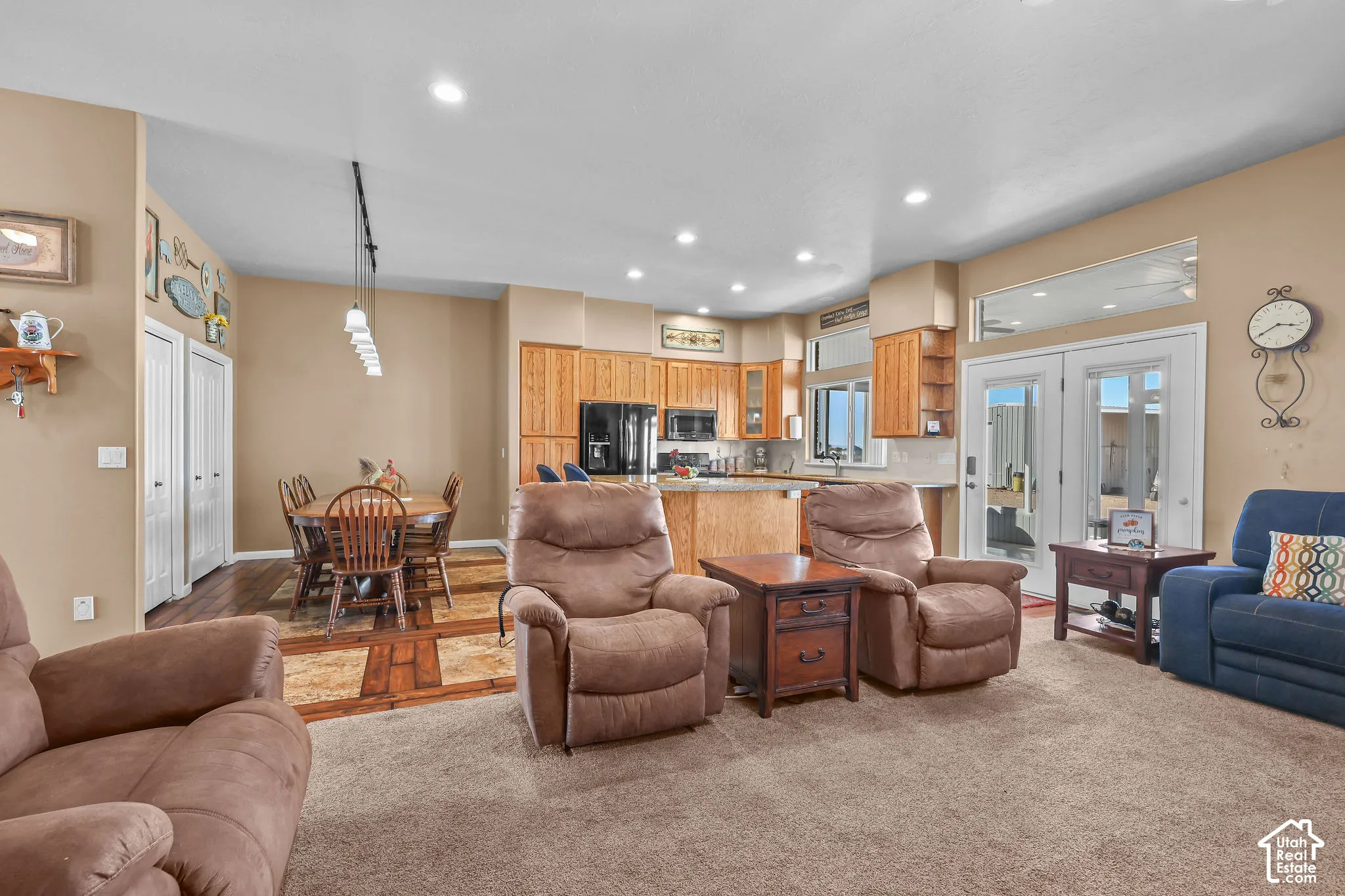 Open-concept kitchen featuring oak cabinetry, a center island with bar seating, recessed lighting, and glass-paneled double doors leading to the exterior