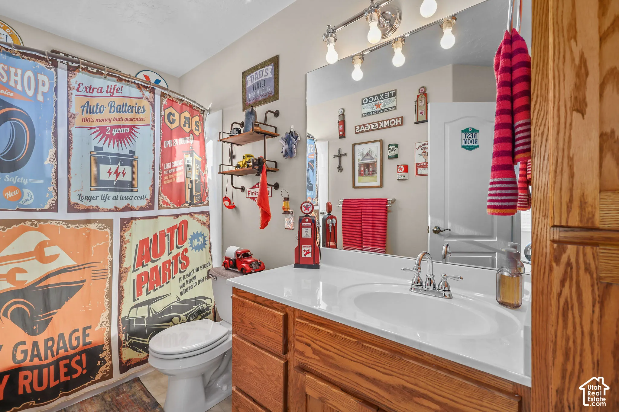 Bathroom featuring a wood vanity with a white countertop, an integrated oval sink, a polished metal faucet, and a large wall-mounted mirror with multi-bulb lighting