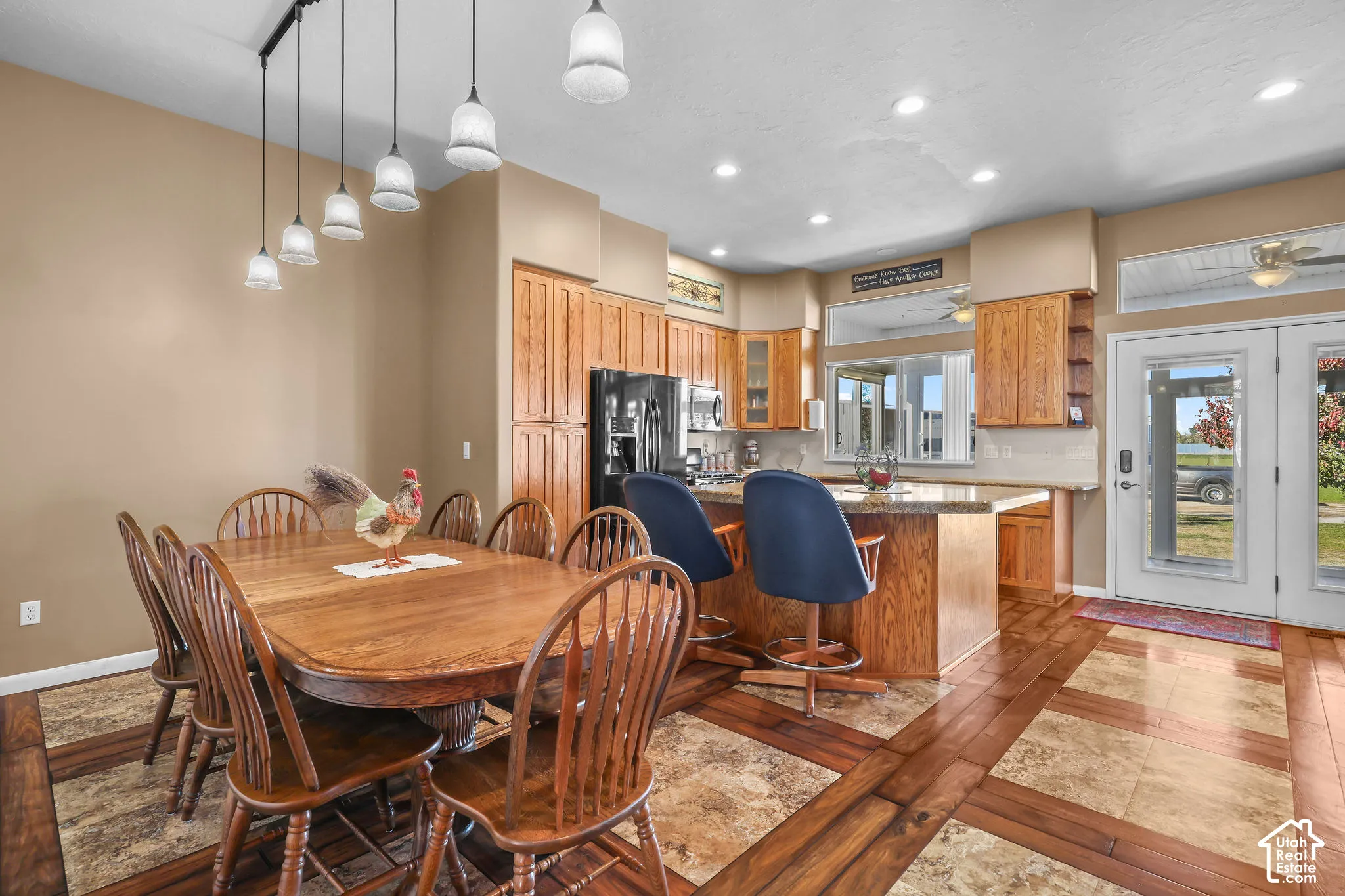 Kitchen featuring solid wood cabinetry, a stone-topped island, tile and wood-look flooring, recessed lighting, and glass pendant fixtures