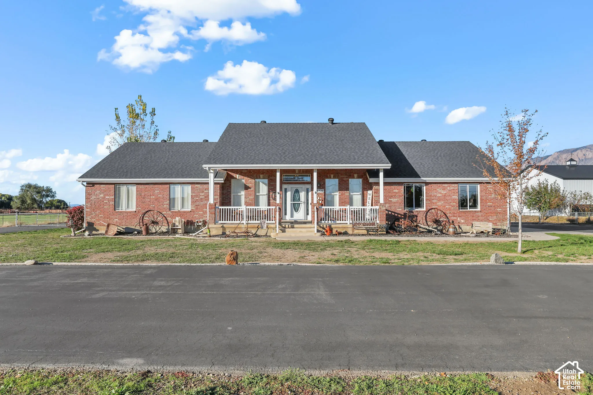 Red brick exterior featuring a covered front porch with white railing, a central gable roofline, and an asphalt shingle roof