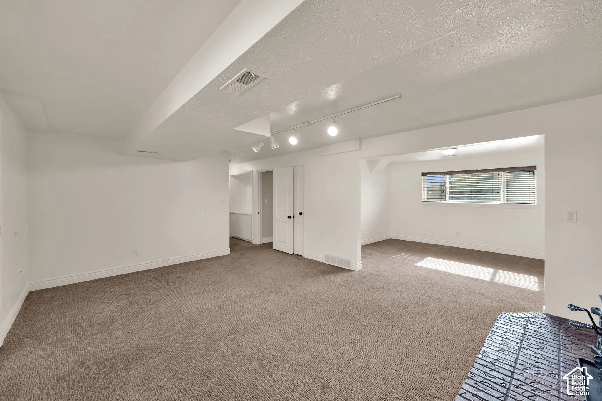 Neutral-toned carpeting, adjustable track lighting, double-door closet, and horizontal sliding windows