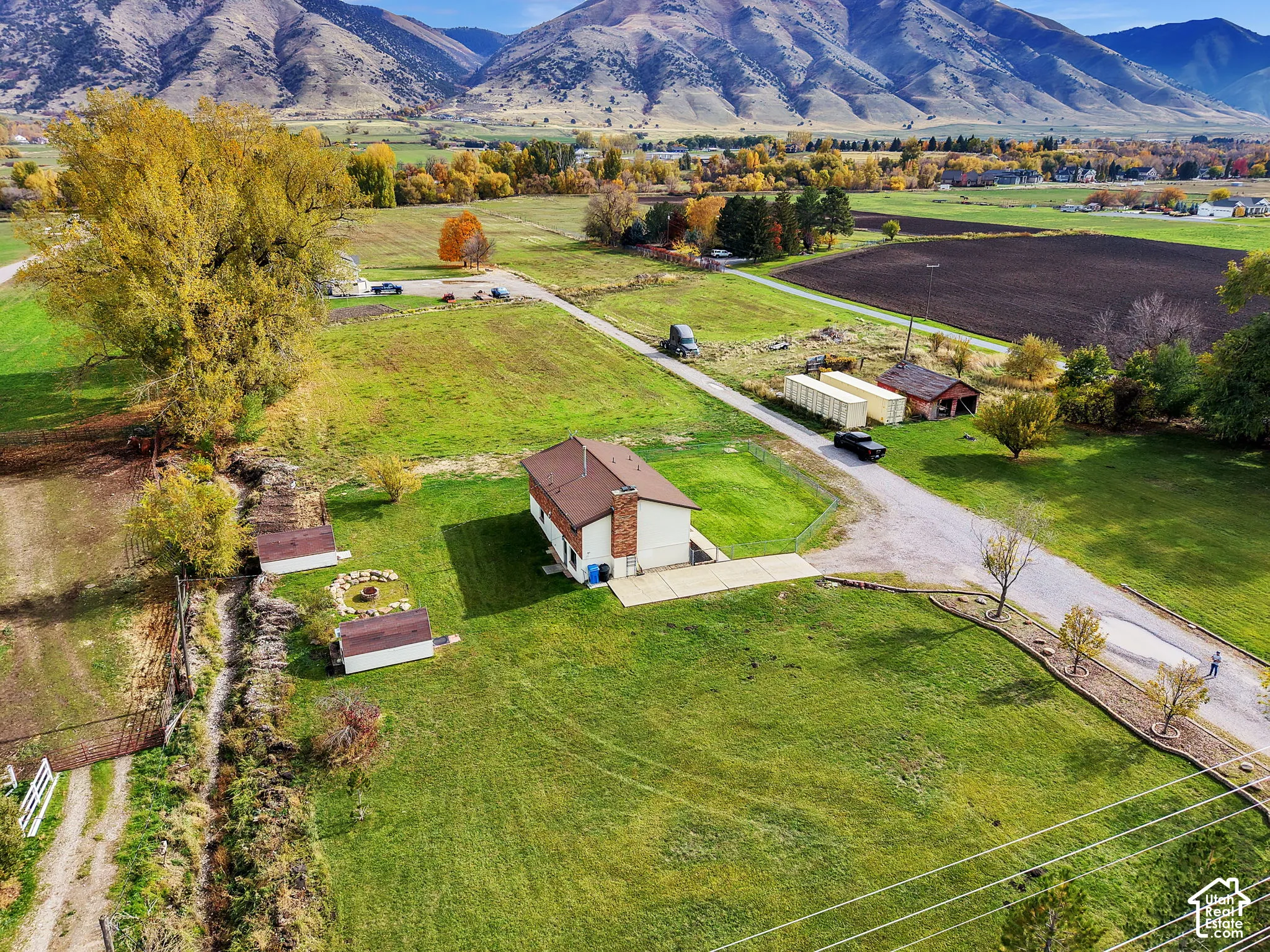 Expansive acreage featuring a masonry chimney, concrete patio, mature trees, and mountain backdrop