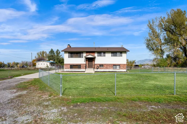 Split-level exterior featuring a combination of brick and horizontal siding, a concrete driveway, and a fenced yard