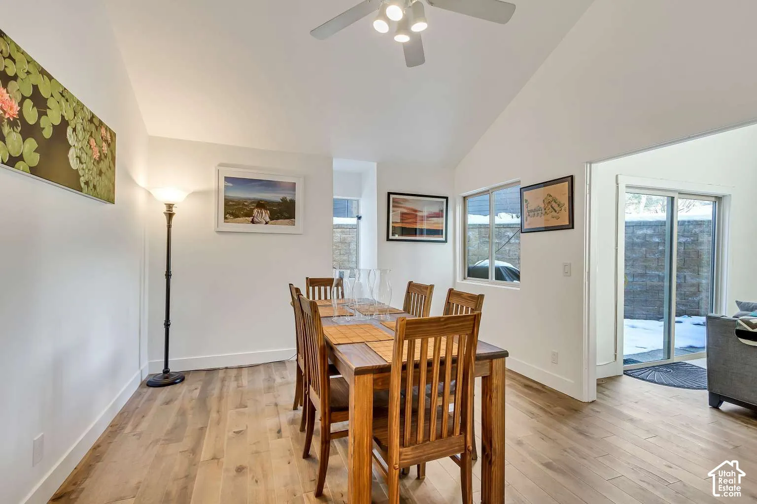 Vaulted ceiling with a central multi-light fan, wood-finish flooring, and sliding glass patio door