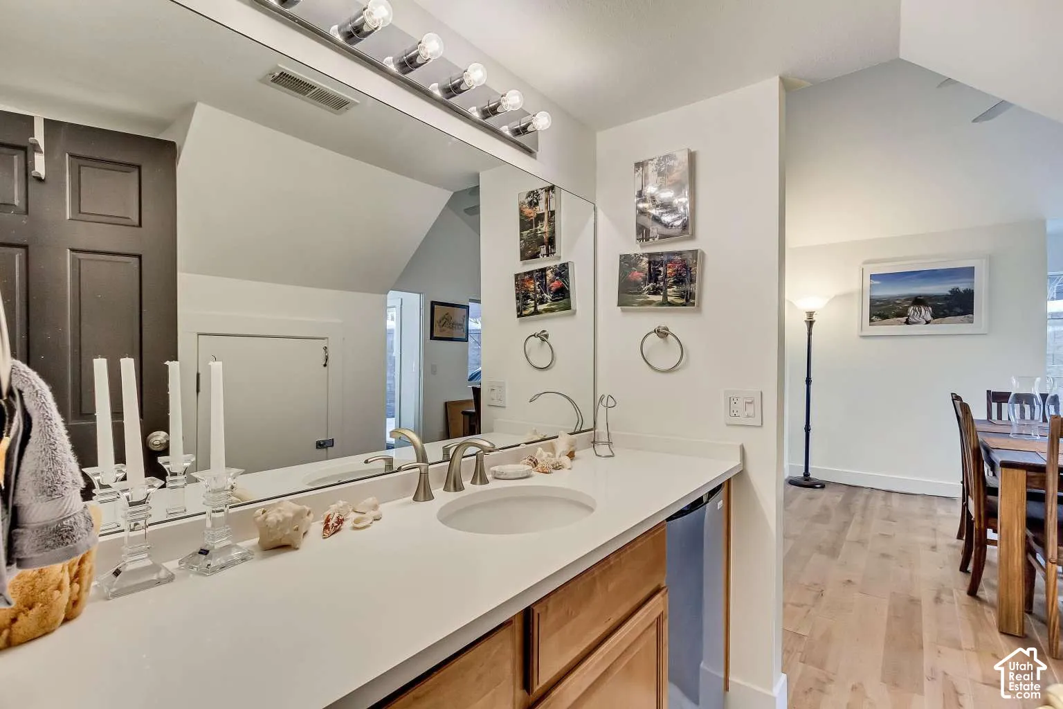 Bathroom vanity featuring a stone countertop, an undermount circular sink, a full-width mirror, and a multi-bulb light fixture