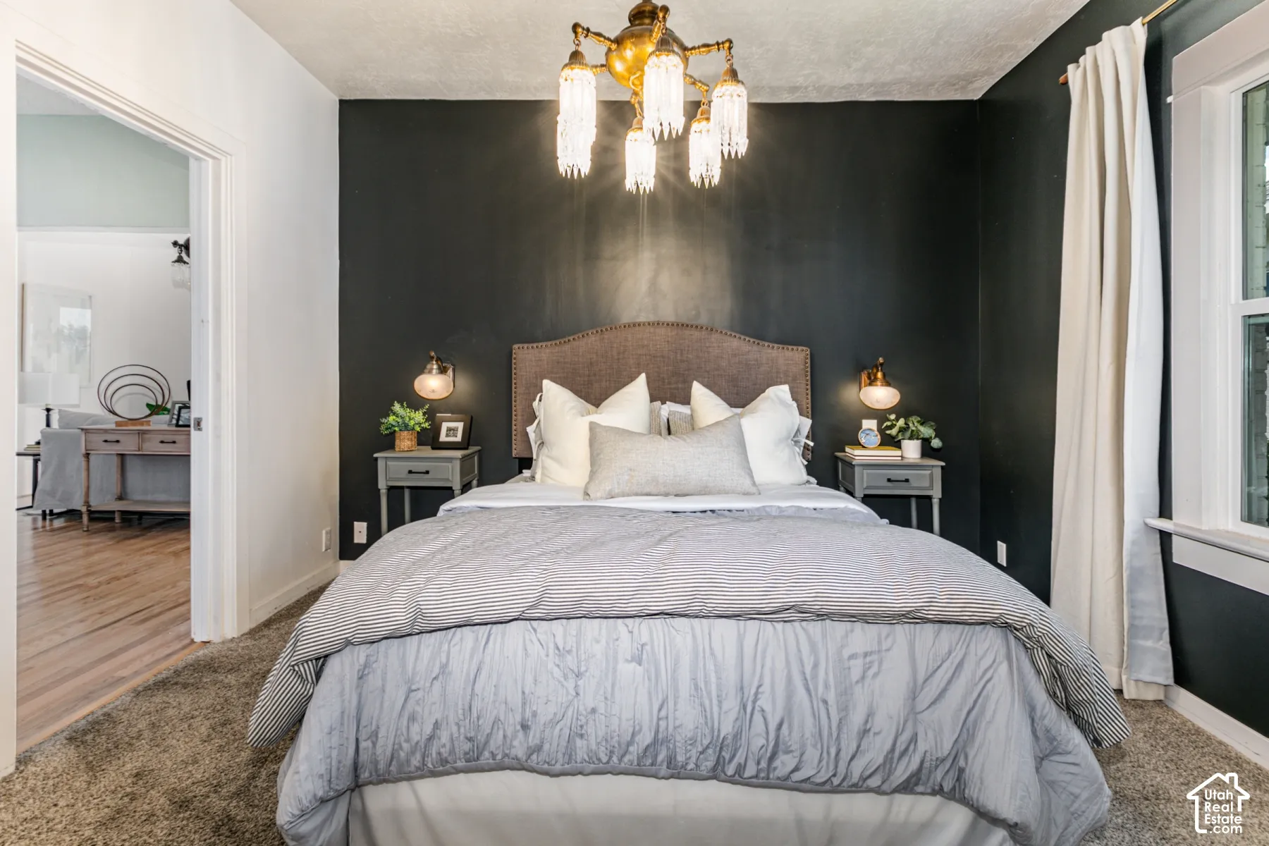 Multi-light crystal and brass-finish chandelier, contrasting dark accent wall, and wall-mounted brass-finish reading lights