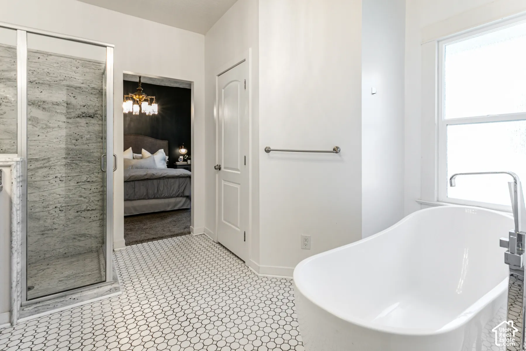 Bathroom featuring a freestanding soaking tub with a floor-mounted faucet, a glass-enclosed shower with stone-surround tile, and penny-round mosaic tile flooring