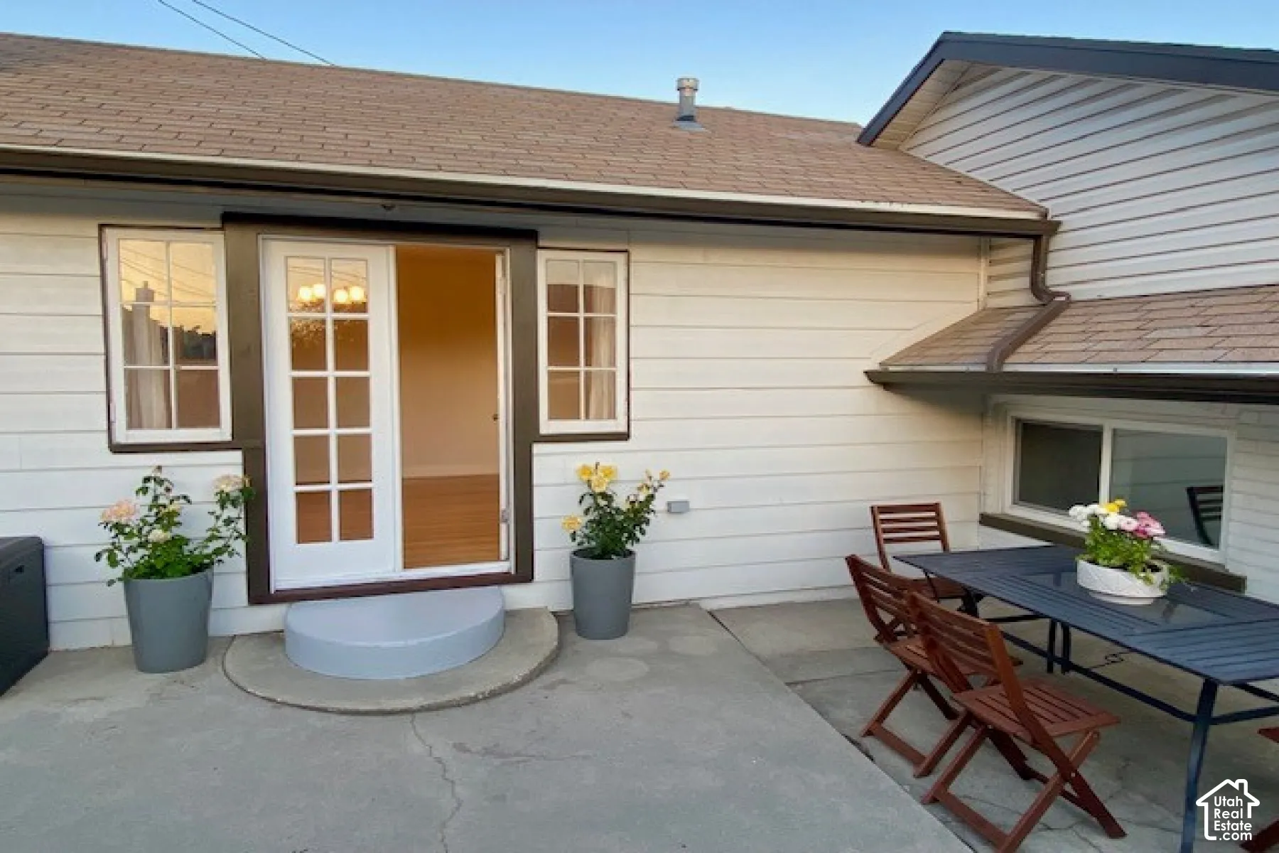 Concrete patio featuring horizontal lap siding, a glass-paned door, and divided light windows