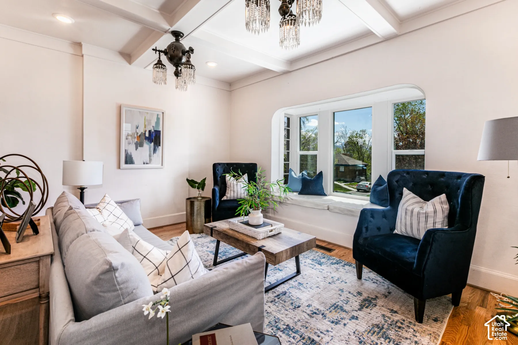 Coffered ceiling featuring recessed lighting, multi-tiered iron chandelier, and integrated bay window with built-in window seat and wood-finish flooring