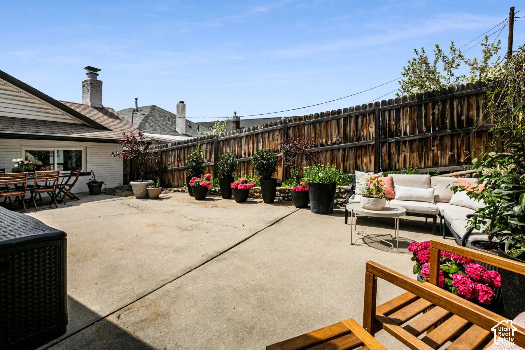 Concrete patio with a wood privacy fence, stone-retaining wall, and exterior brick siding